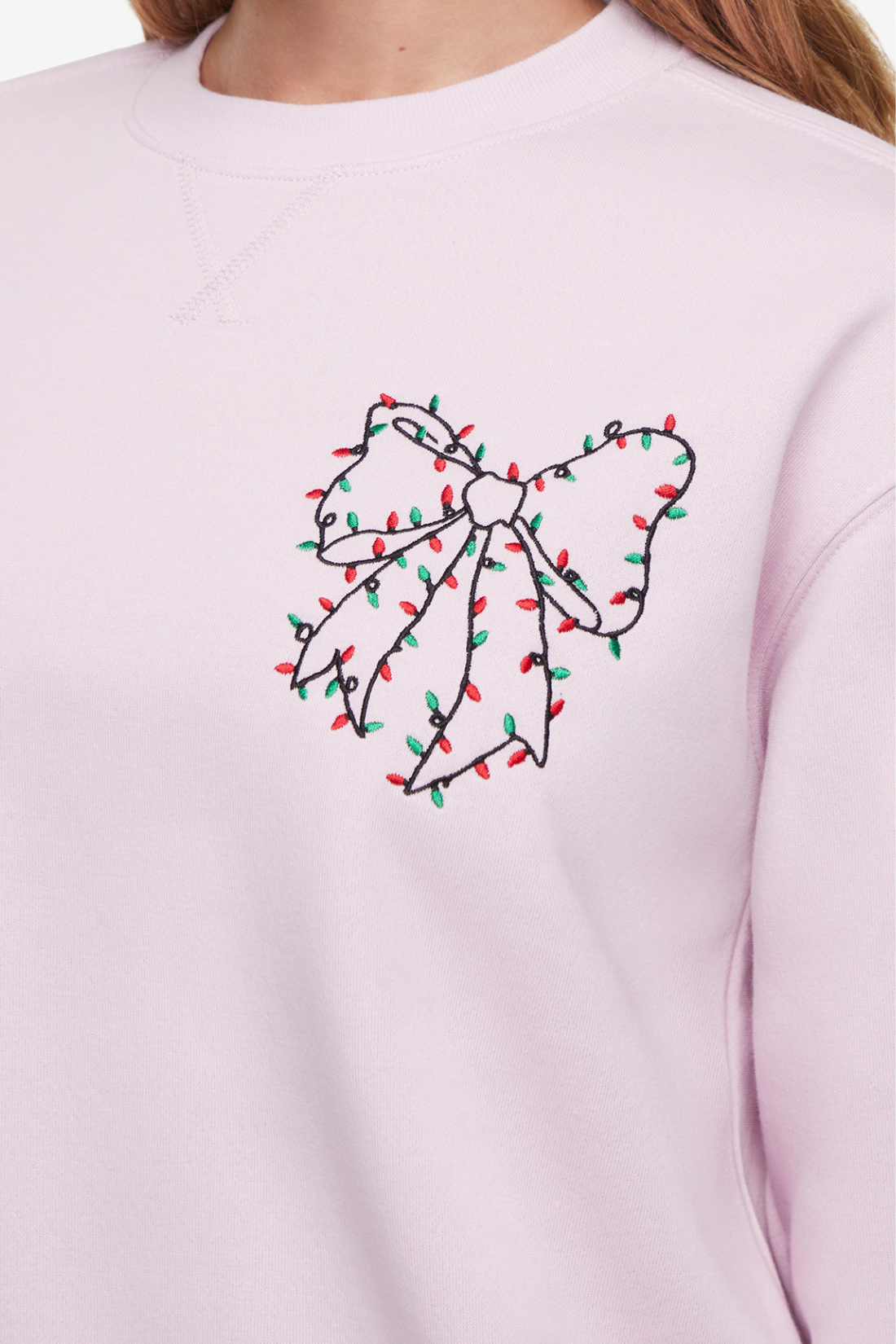 Close up of light pink sweatshirt with a bow design made of Christmas lights on the chest