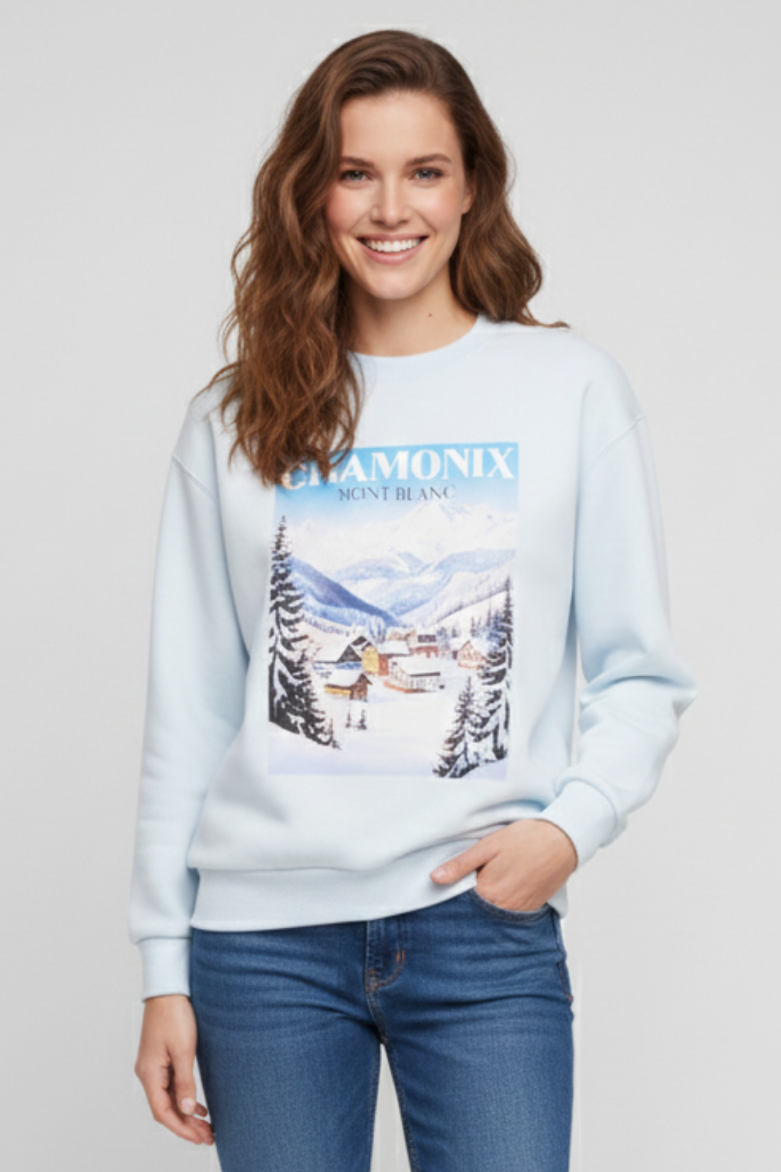 Woman wearing a light blue sweatshirt with a mountain graphic and &