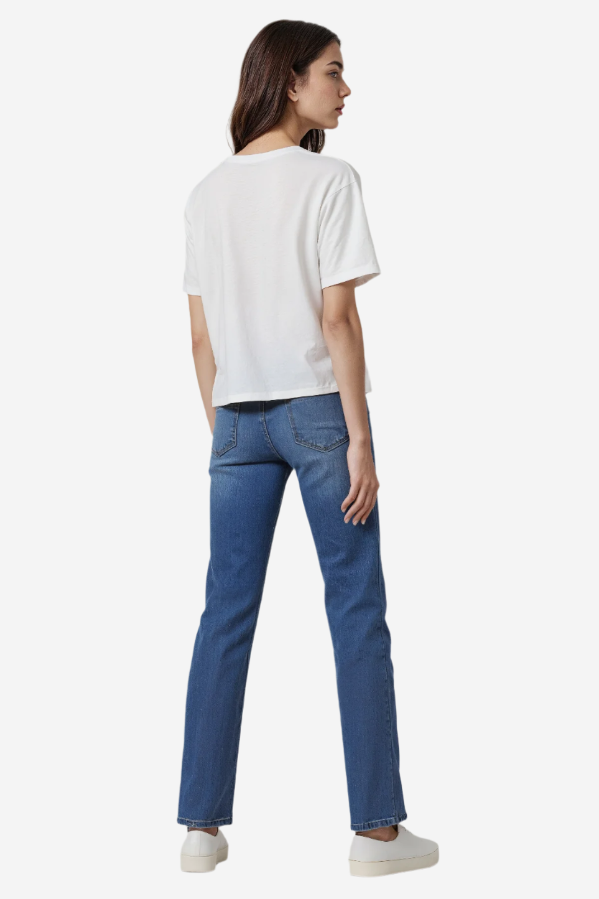 Woman wearing a white t-shirt and blue jeans on a plain background