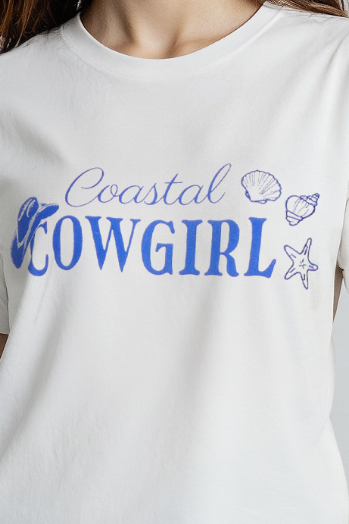 A woman wearing a white crop top with the text &