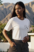 A woman wearing a white crop tee with the text &