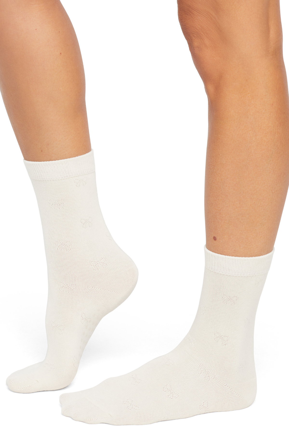 White socks with embossed bow print worn by a woman on a white background.