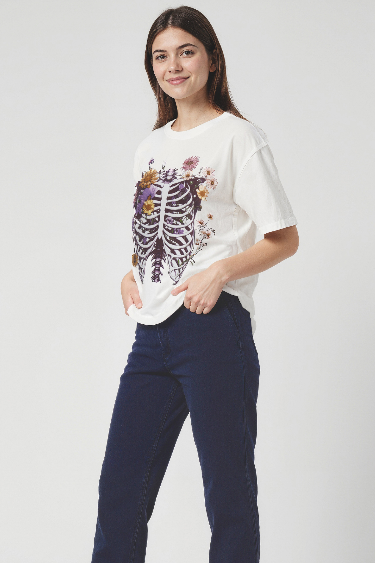 Woman wearing a white t-shirt with a colorful graphic rib cage design on a plain background