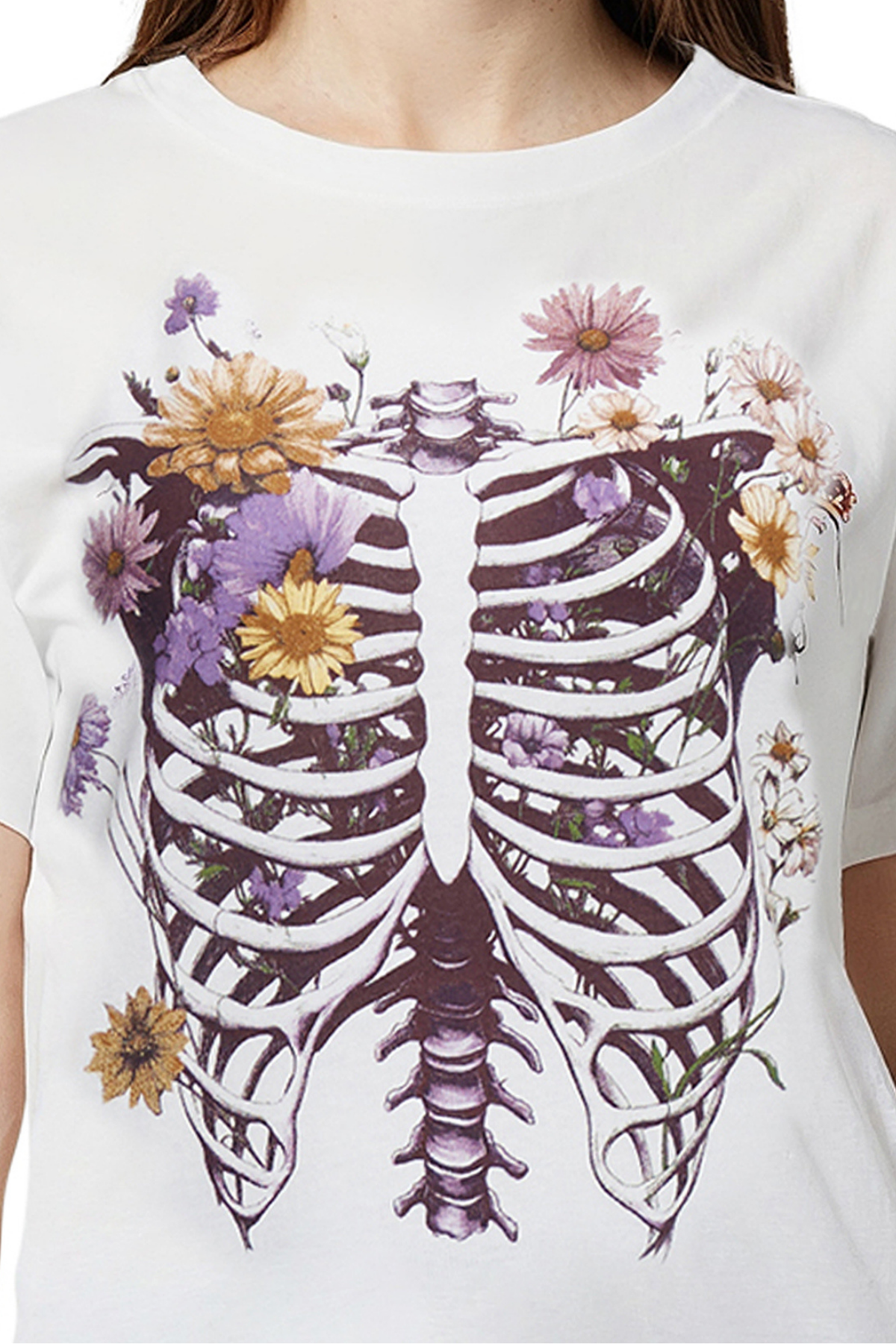 Closeup of white T-shirt with a skeleton rib cage and floral design on a white background