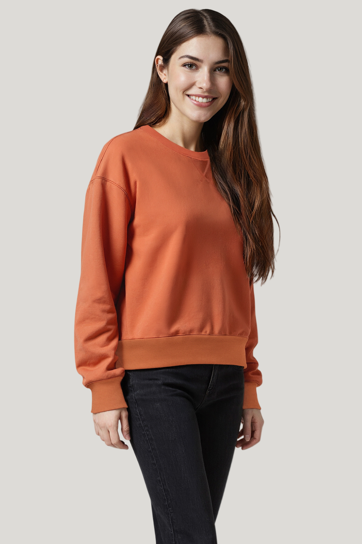 Woman wearing an orange sweatshirt and black pants on a white background