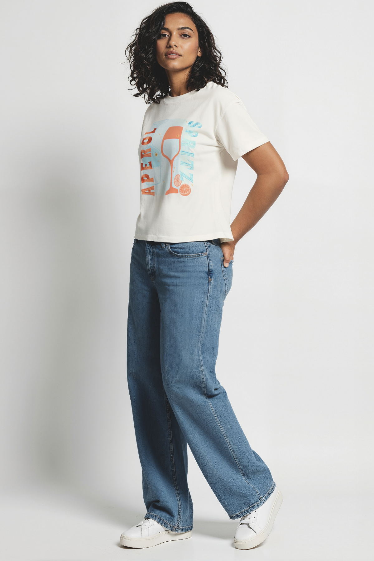Woman wearing white t-shirt with a colorful graphic of a wine glass and &