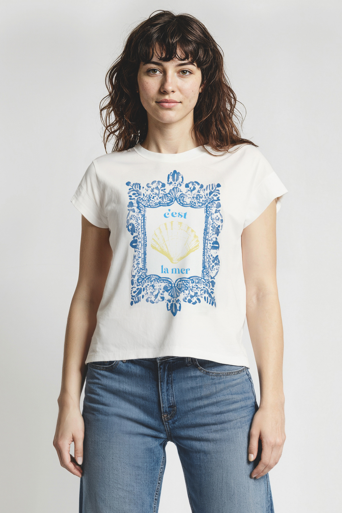 Woman wearing white t-shirt with blue frame graphic design featuring a yellow shell and &