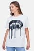 A woman wearing a white t-shirt with the black large vampire lips with drips graphic paired with denim jeans.