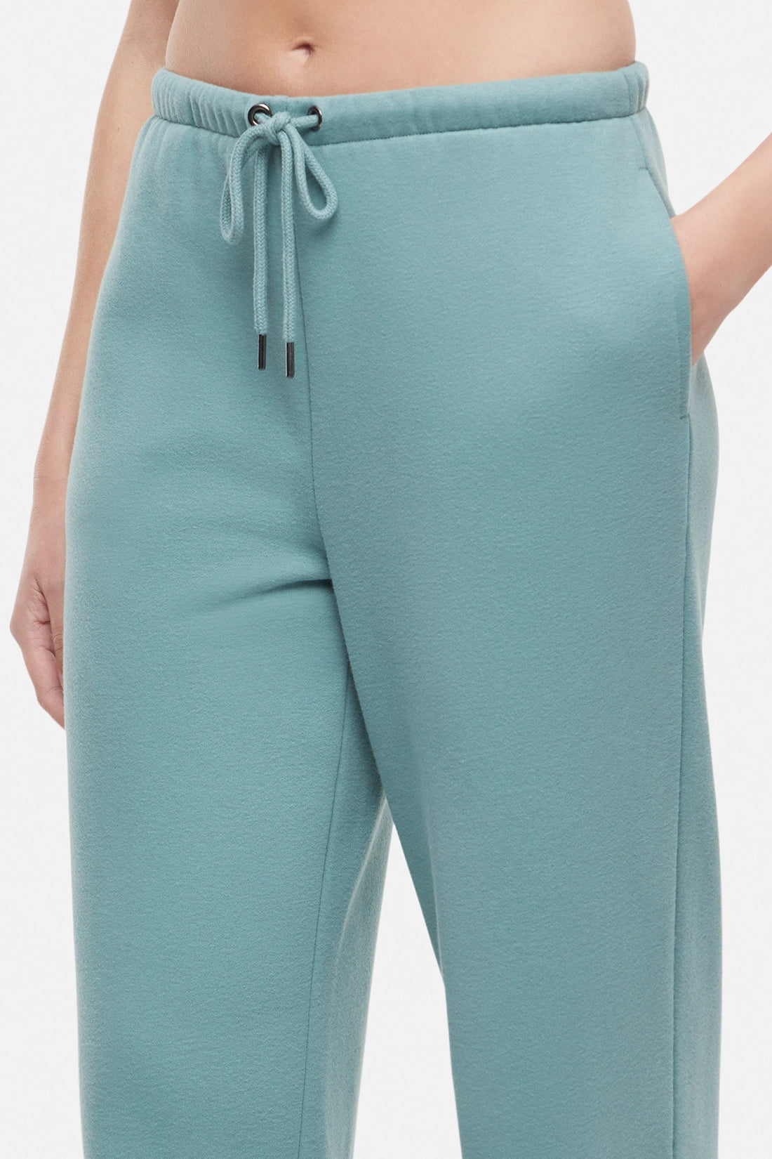 Close up of woman wearing teal wide-leg drawstring sweatpants on a white background