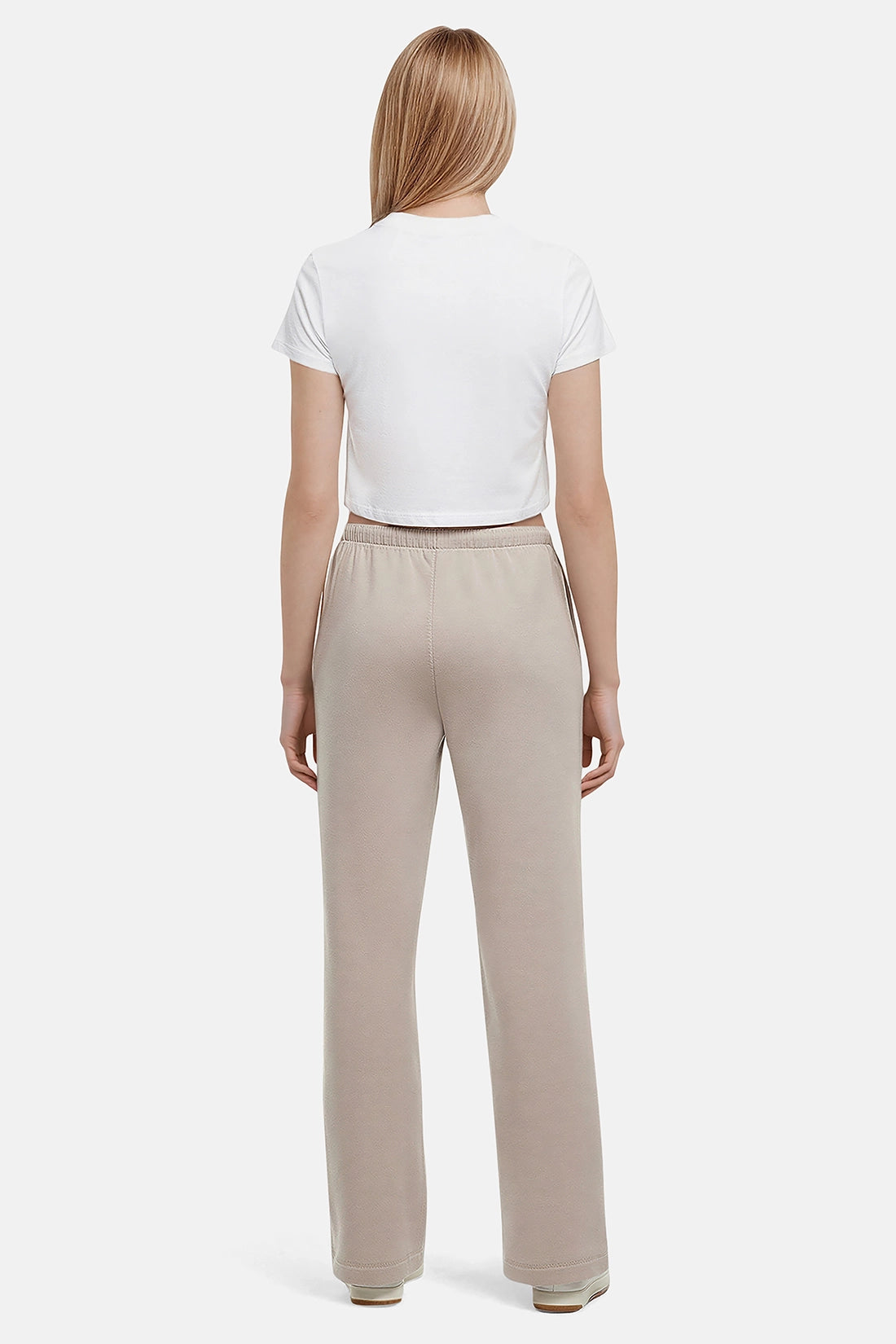 Back of woman wearing a white cropped t-shirt and beige wide-leg drawstring sweatpants on a white background