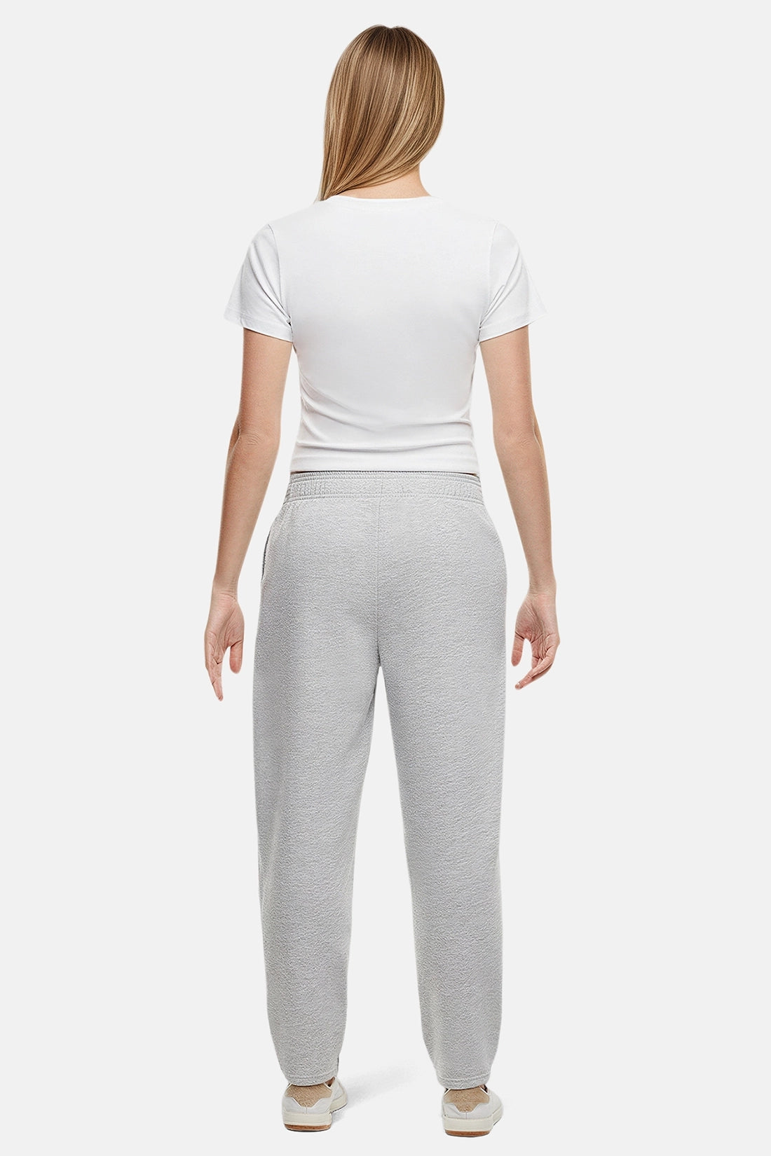 Back of woman wearing a white t-shirt and heather grey tapered leg pants on a white background