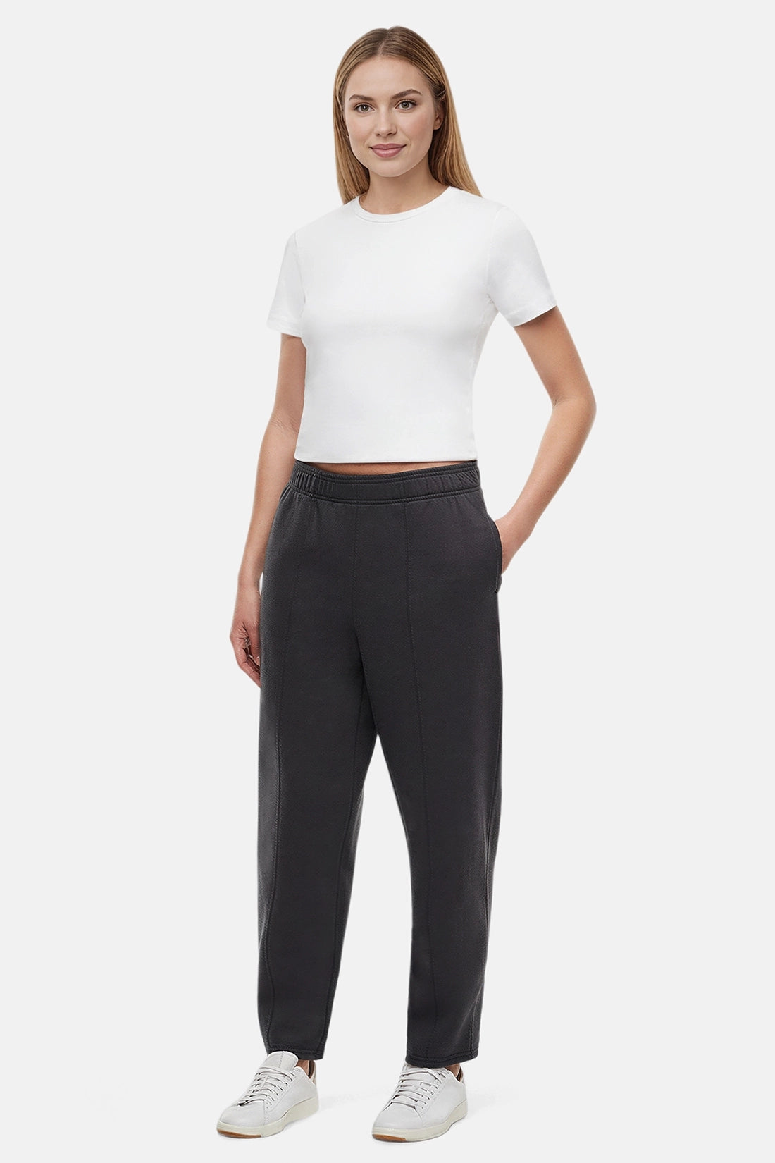 Woman wearing a white t-shirt and black tapered leg pants on a white background