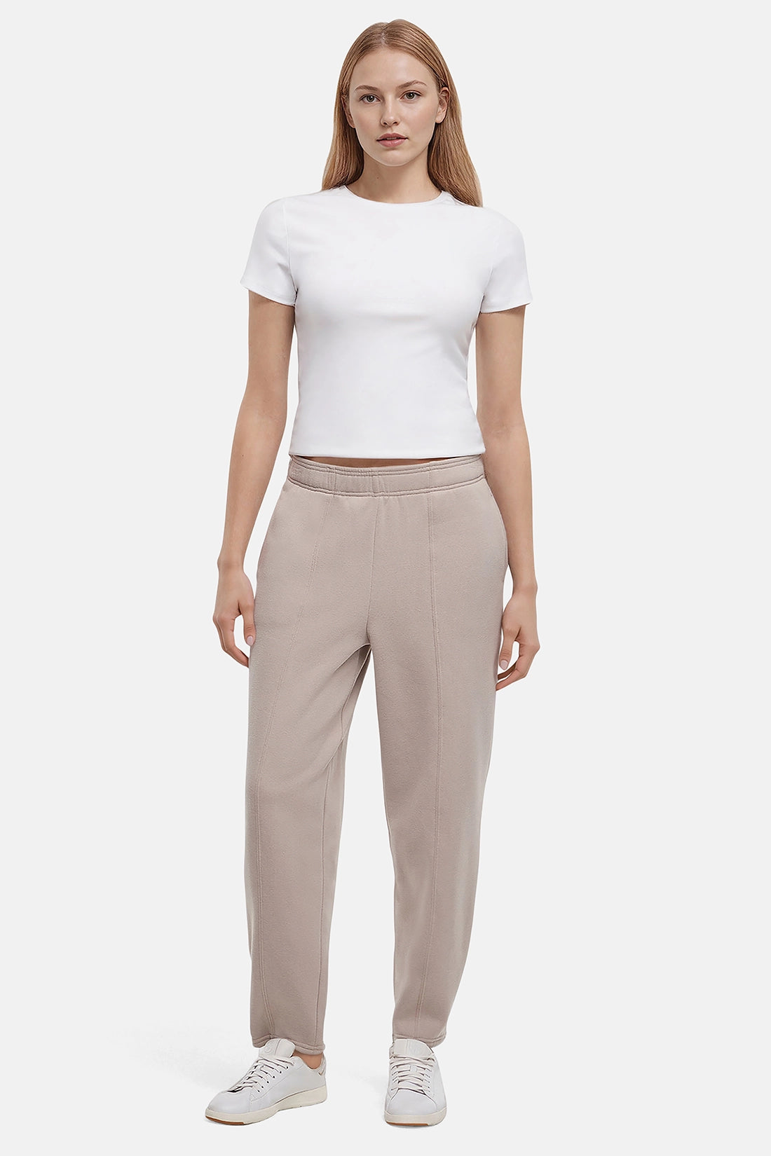 Woman wearing a white t-shirt and beige tapered leg pants on a white background
