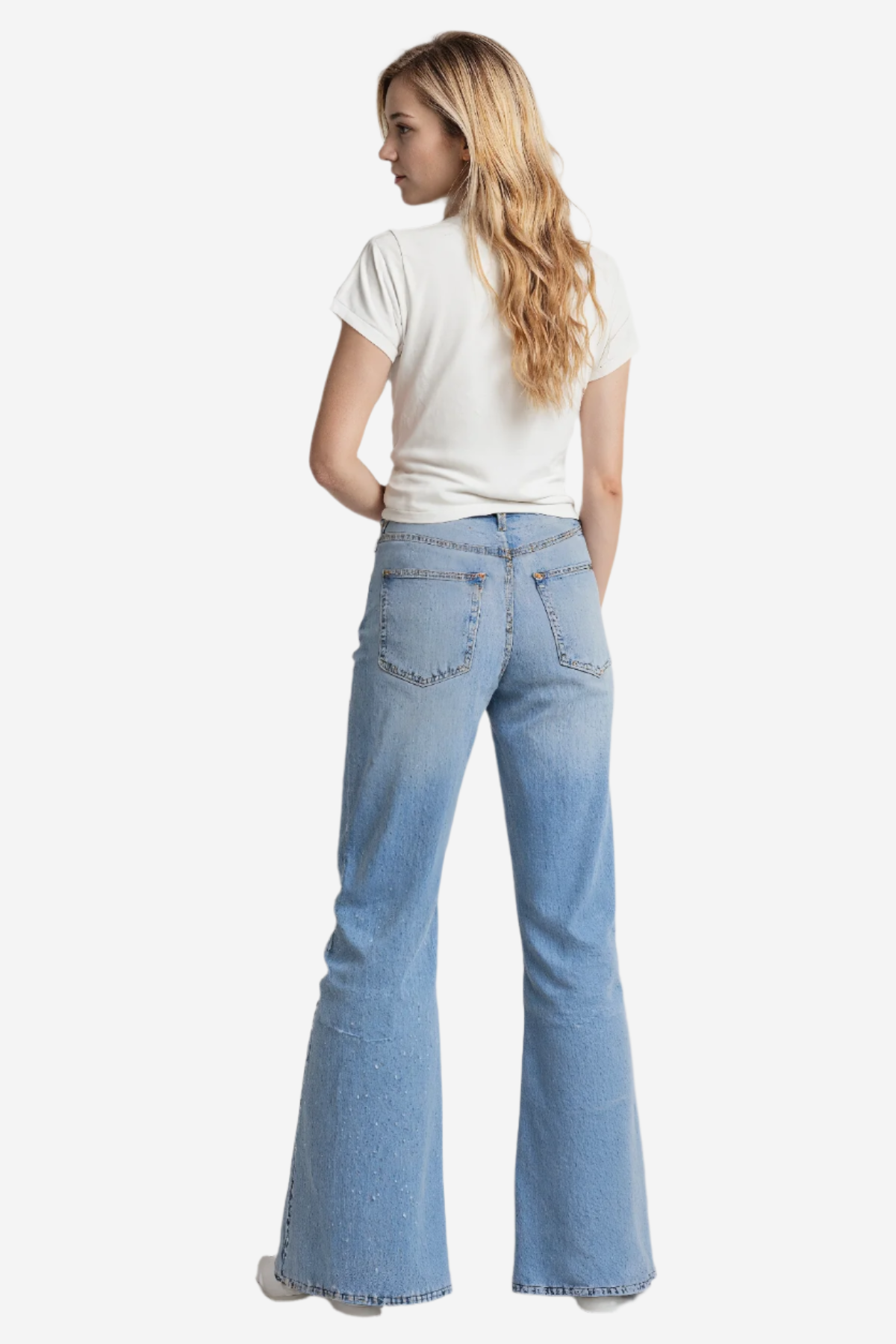 Woman wearing a white t-shirt and blue jeans on a plain background.
