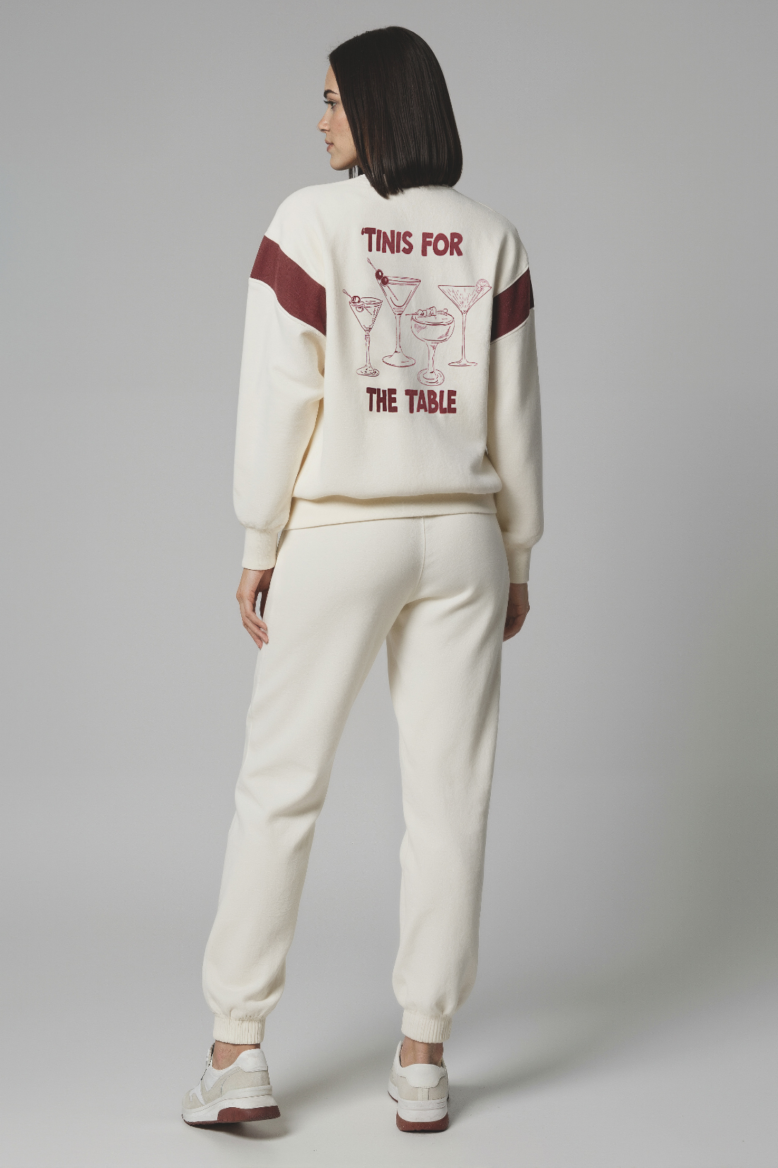 Woman wearing a cream sweatshirt with red 4 cocktails graphic and text &
