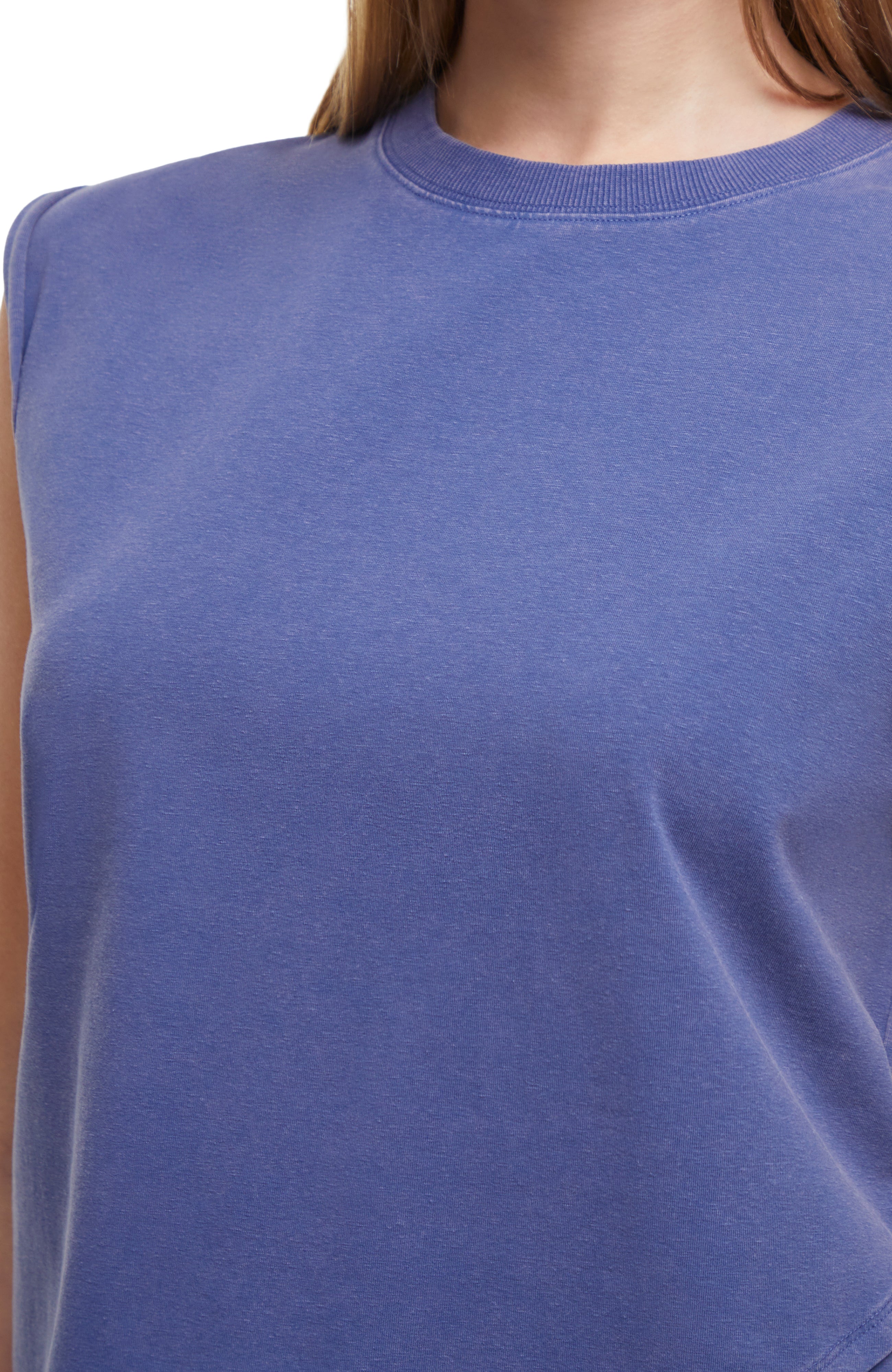Close up front view of woman wearing a gray-blue sleeveless asymmetrical top and pants on a white background.