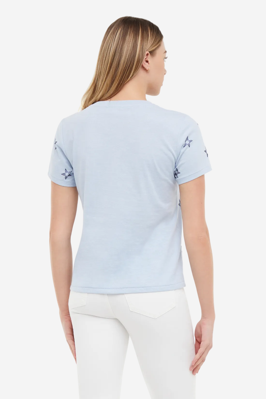 Back of woman wearing a light blue t-shirt with blue rhinestone star patterns on sleeves, standing against a white background