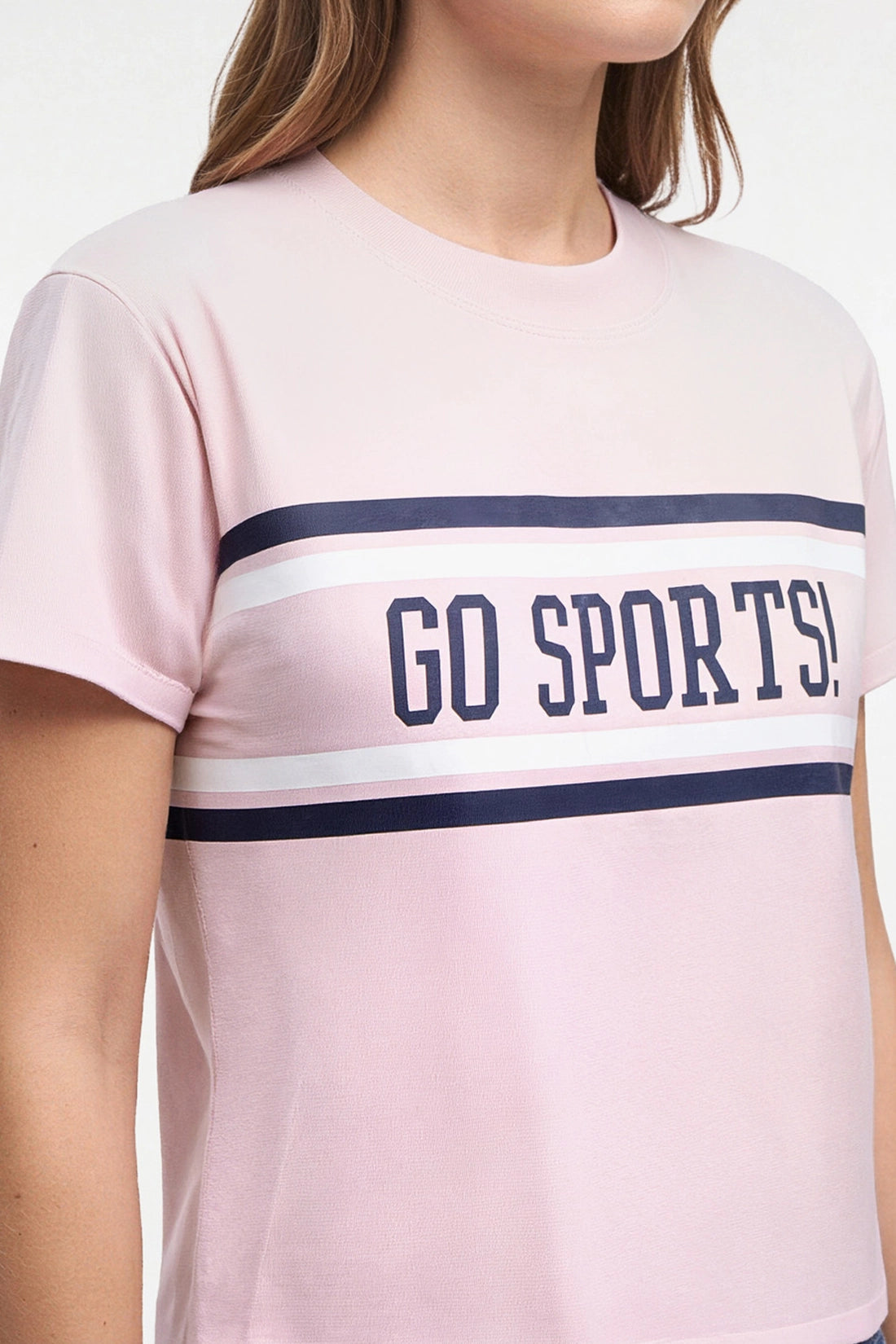 A woman modeling a light pink short-sleeve crop top with a navy blue stripe and &