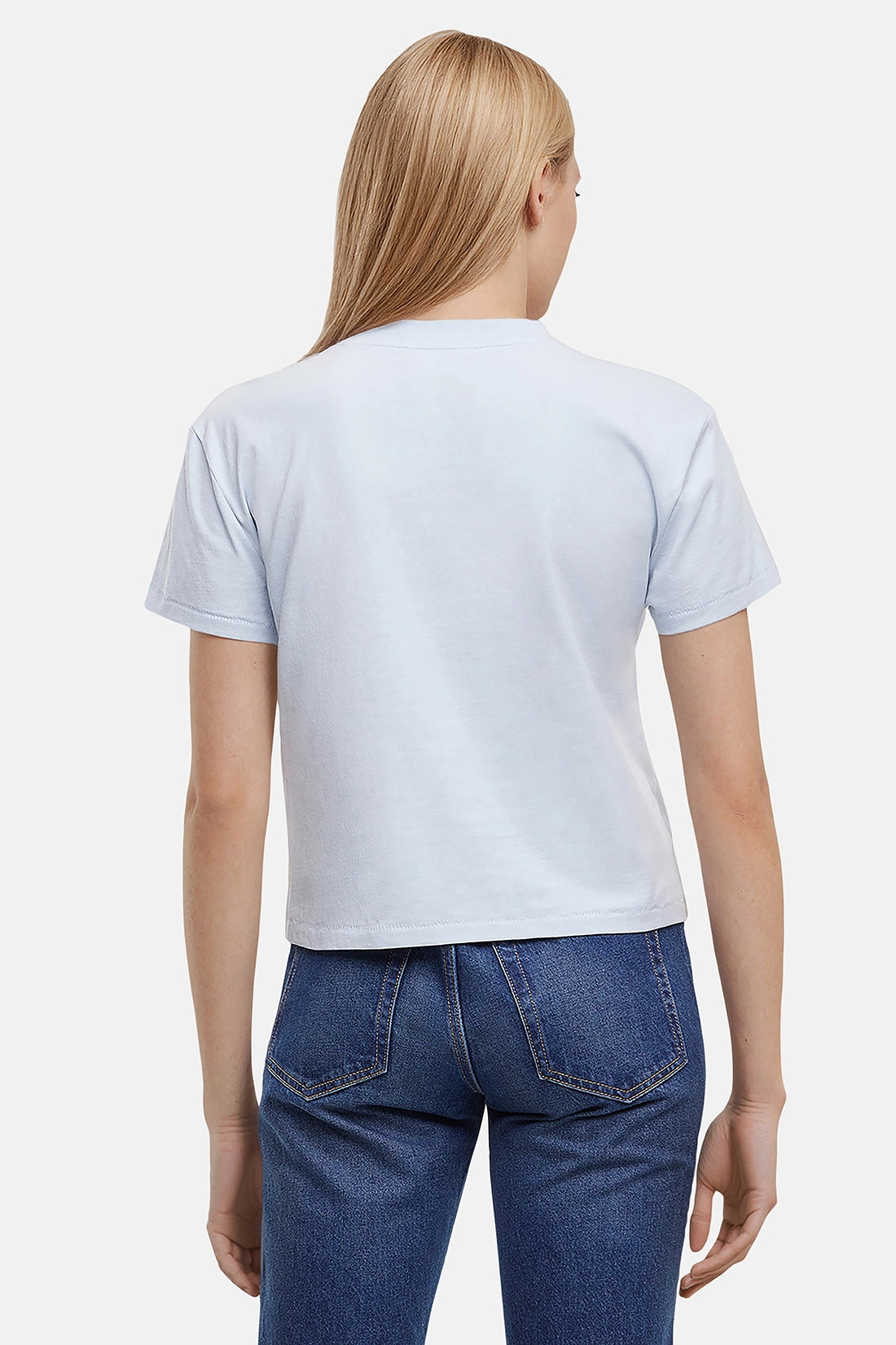 Back of woman wearing a light blue t-shirt and blue jeans on a white background