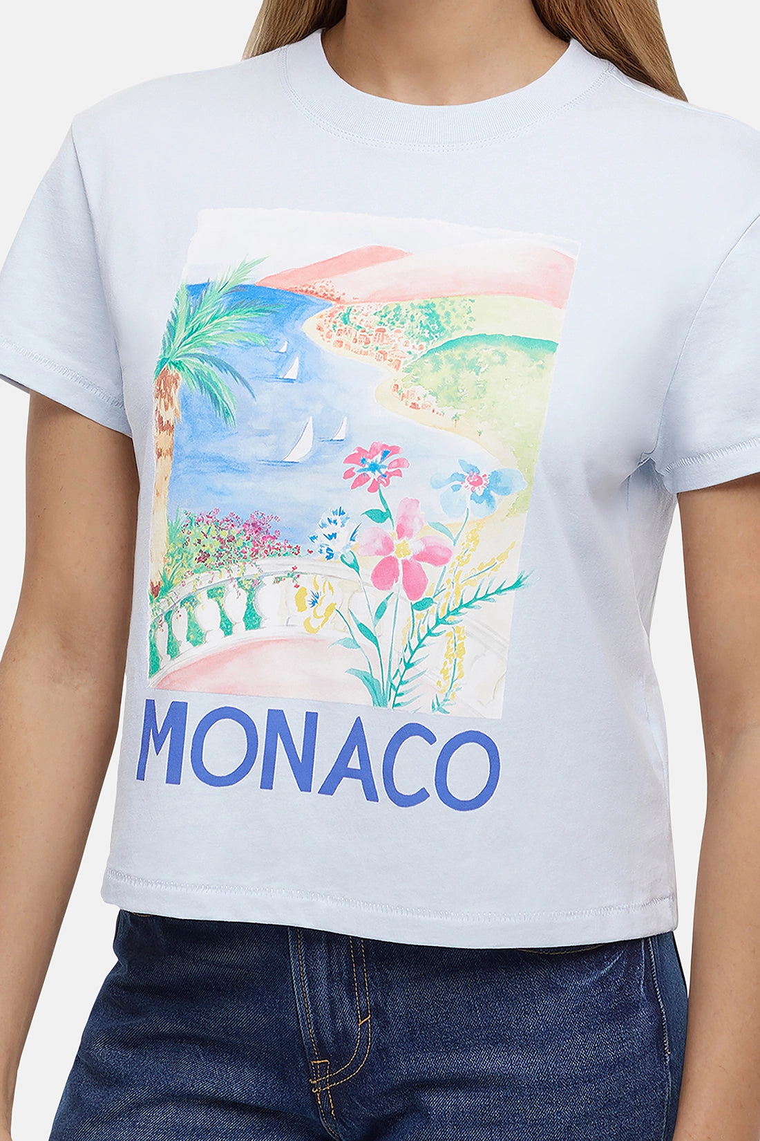Close up light blue t-shirt with colorful beach, flowers, & sailboats graphic of Monaco and the &