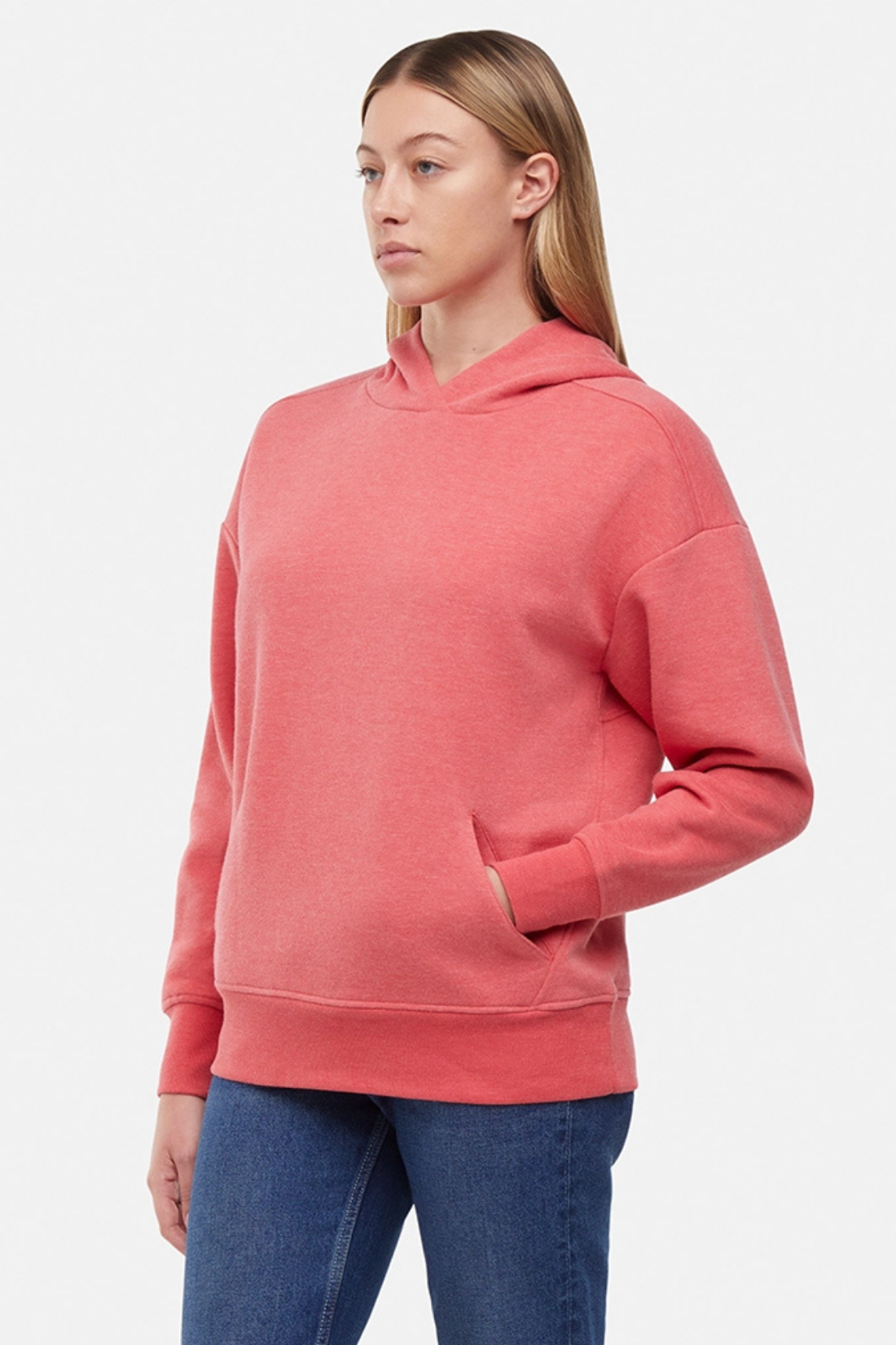 Woman wearing a pink/red hoodie and blue jeans on a white background