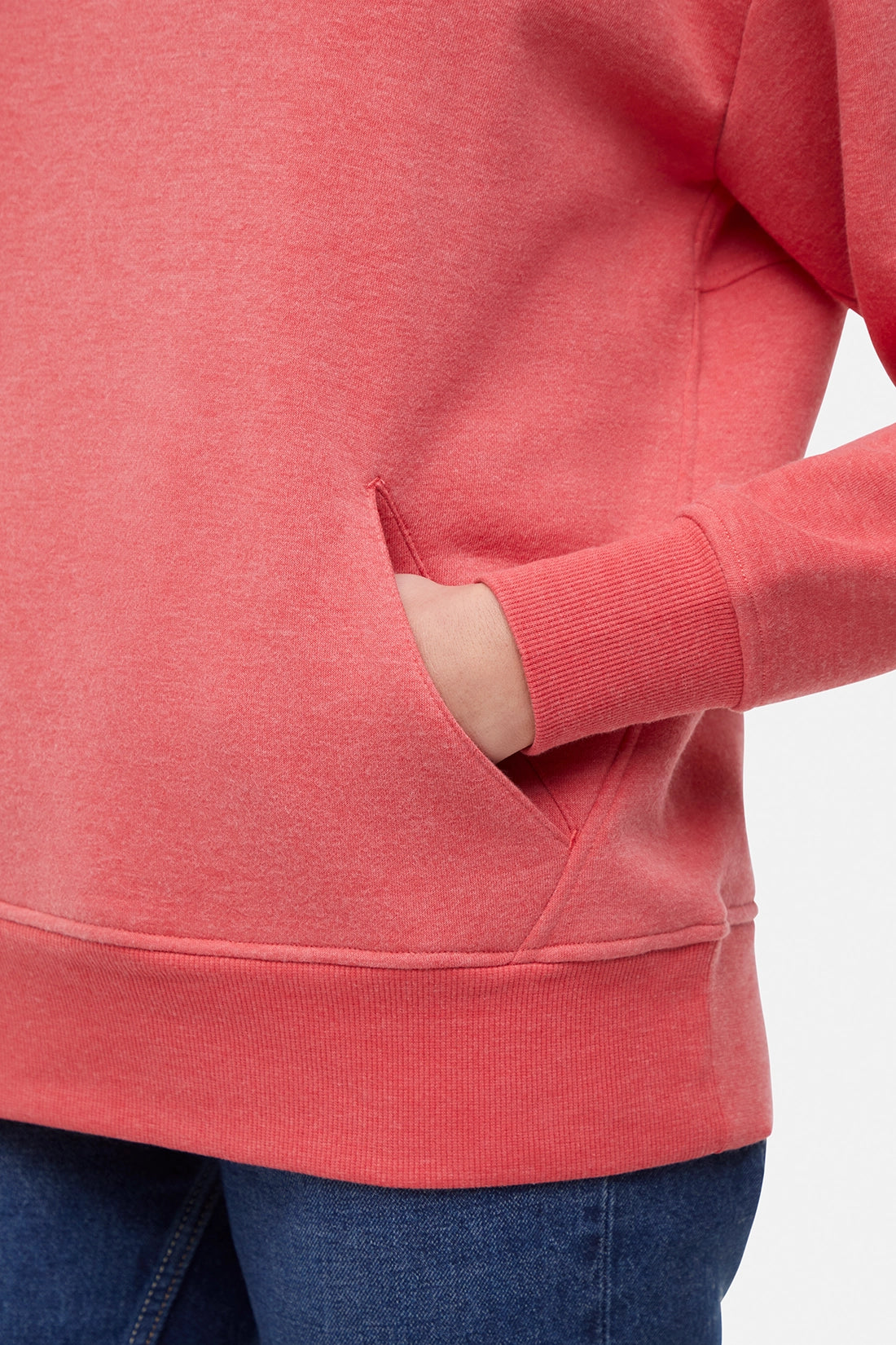 Close-up of a woman wearing a red hoodie with a white background with hand in kangaroo pocket