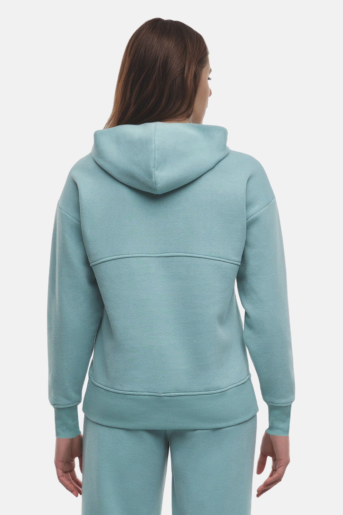 Back of woman wearing a light teal hoodie and pants on a white background