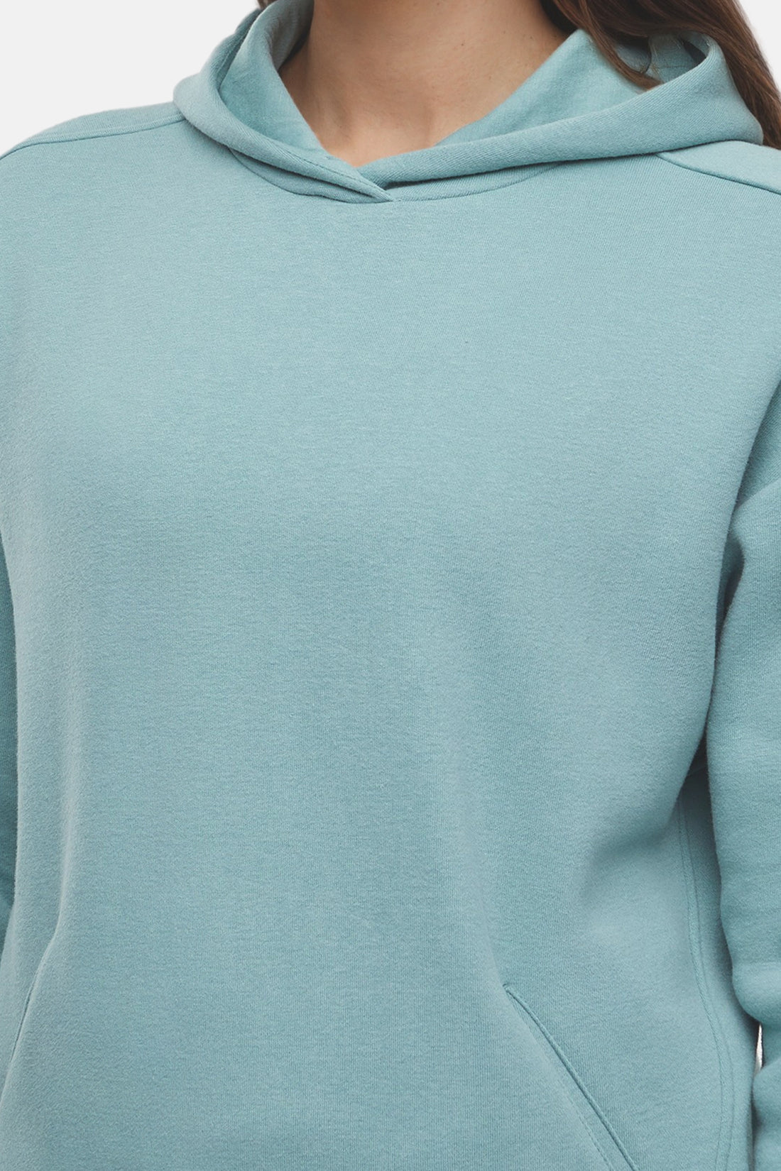 Close up of woman wearing a light teal hoodie and pants on a white background