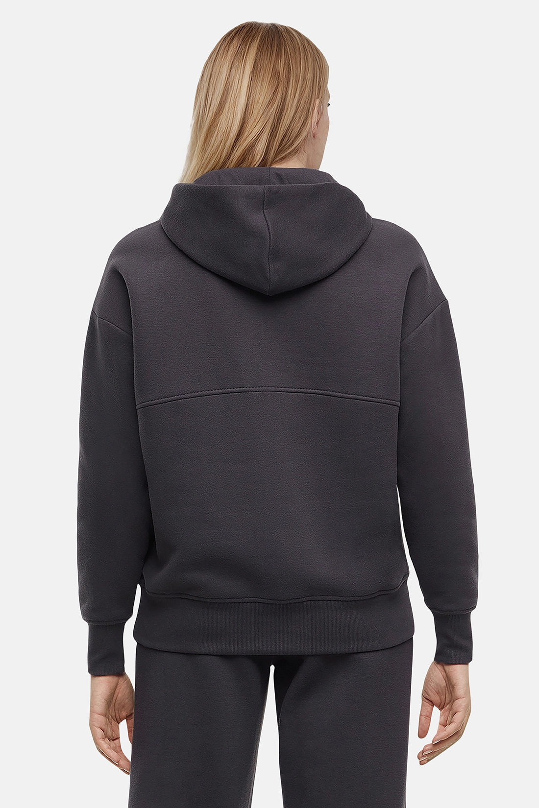 Back of woman wearing a dark gray hoodie on a light gray background