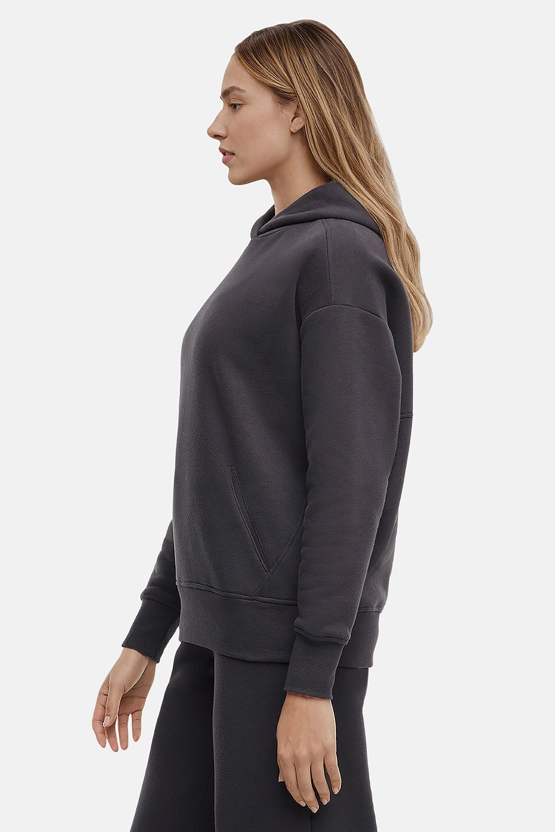 Woman wearing a dark gray hoodie on a light gray background