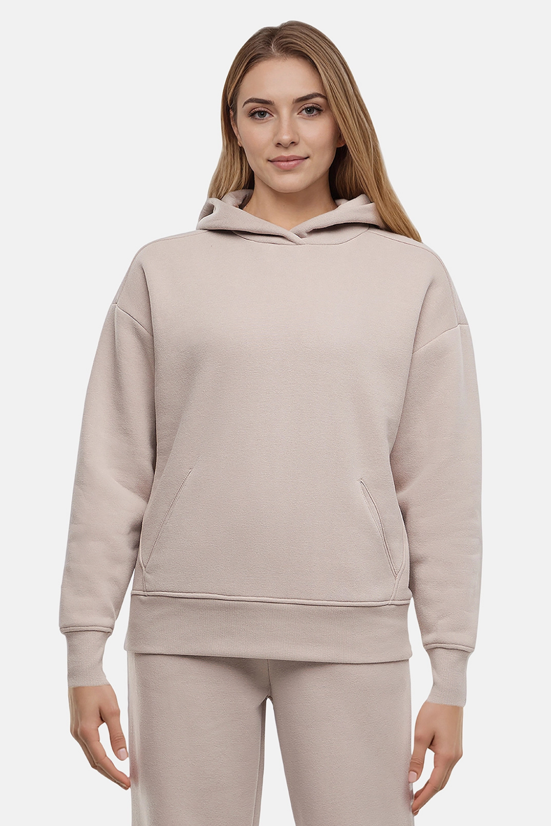 Woman wearing a beige hoodie and pants on a light gray background
