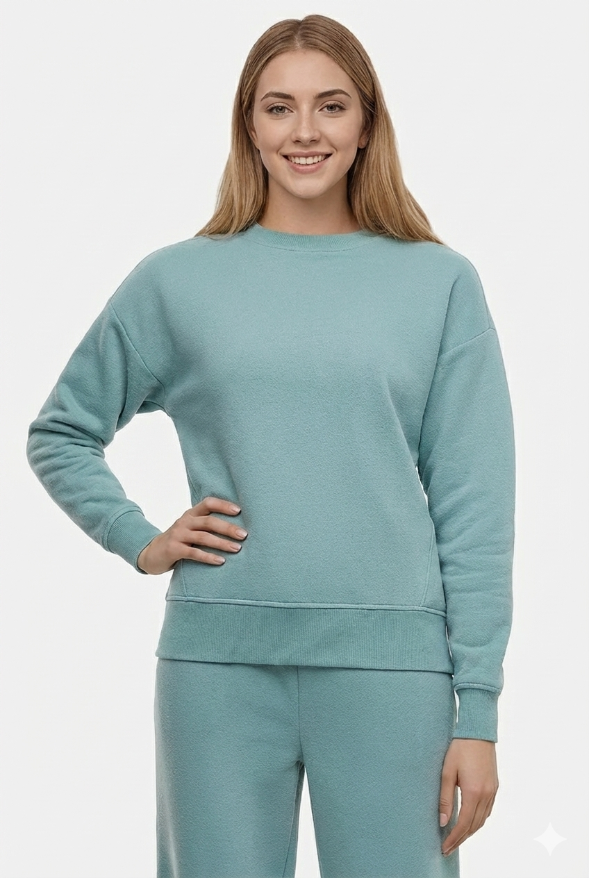 Woman wearing a light teal sweatshirt and pants on a white background