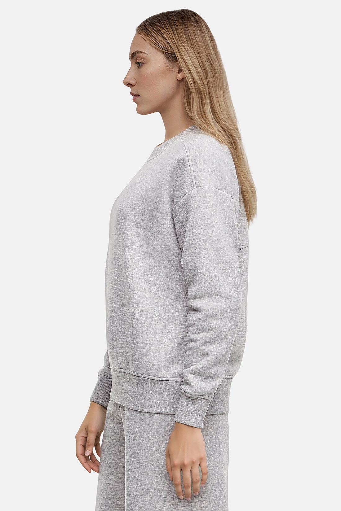 Woman wearing a heather gray sweatshirt and pants on a white background