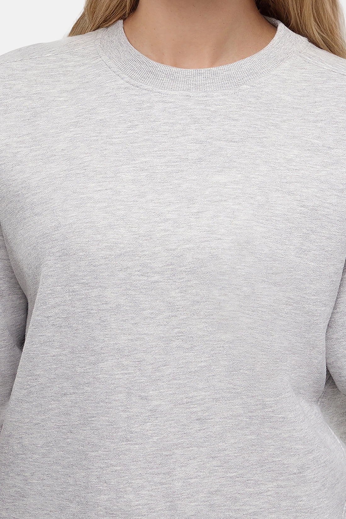 Close up of woman wearing a heather gray sweatshirt and pants on a white background