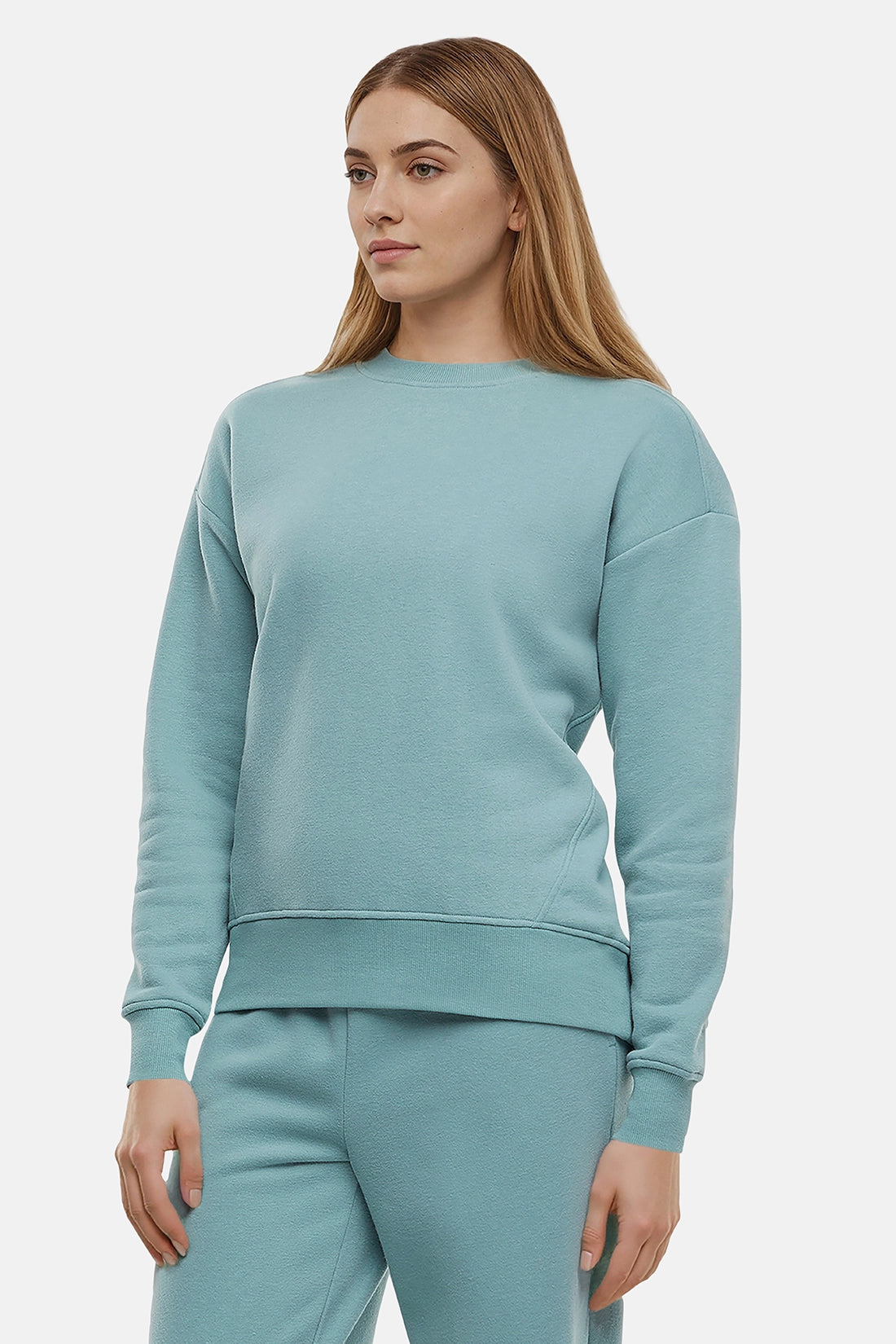 Woman wearing a light teal sweatshirt and pants on a white background