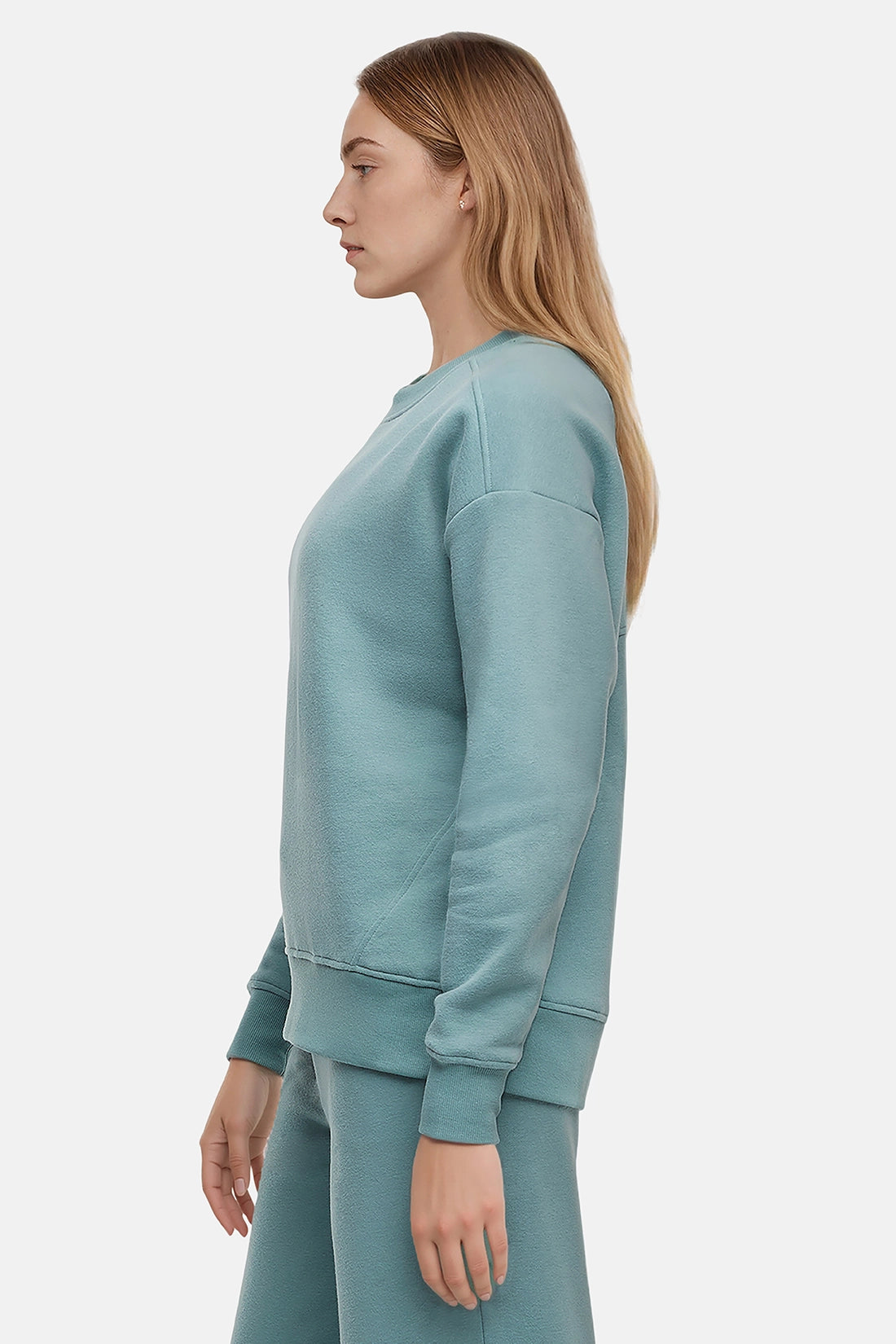 Woman wearing a light teal sweatshirt and pants on a white background