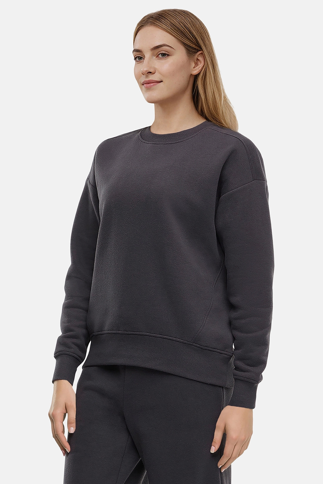 Woman wearing a heather black sweatshirt and pants on a white background