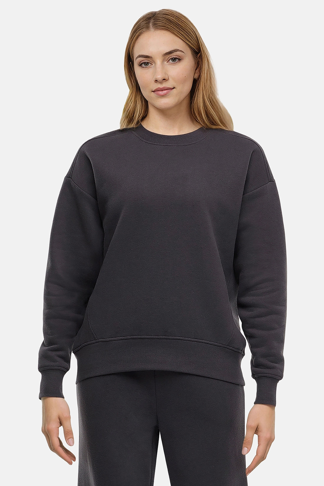 Woman wearing a heather black sweatshirt and pants on a white background