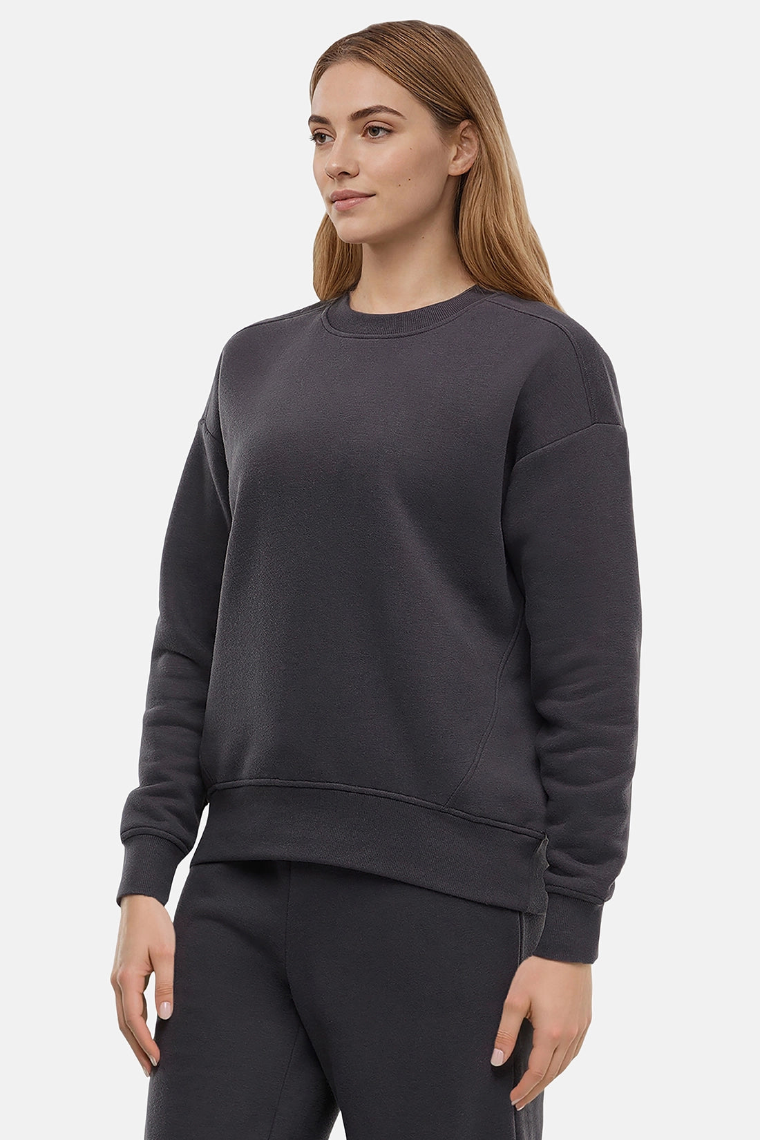 Woman wearing a heather black sweatshirt and pants on a white background