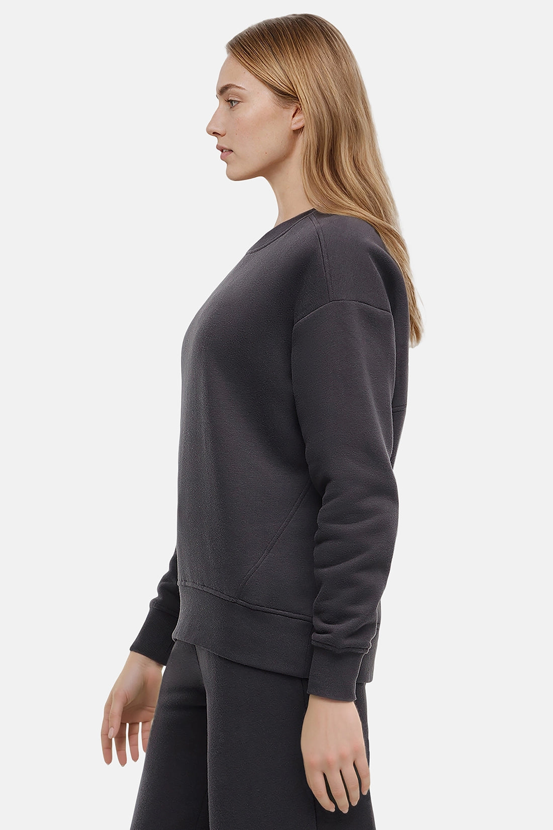 Woman wearing a heather black sweatshirt and pants on a white background