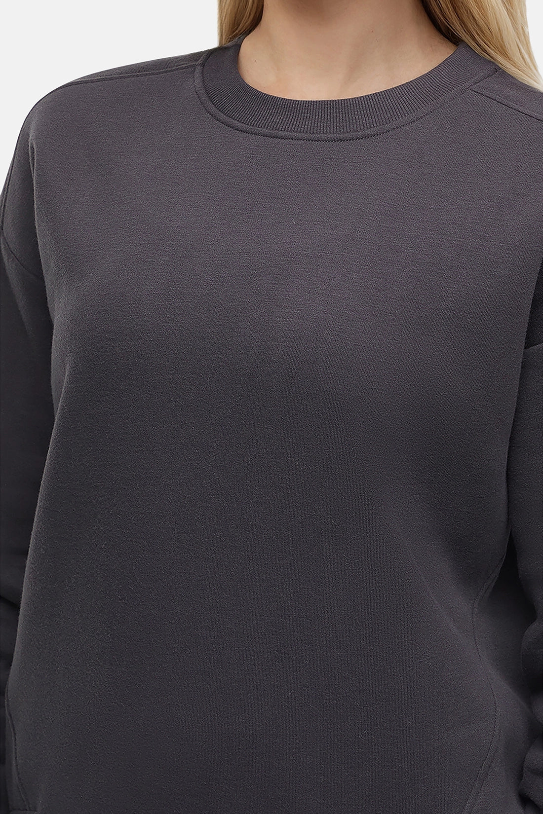 Close up of woman wearing a heather black sweatshirt and pants on a white background