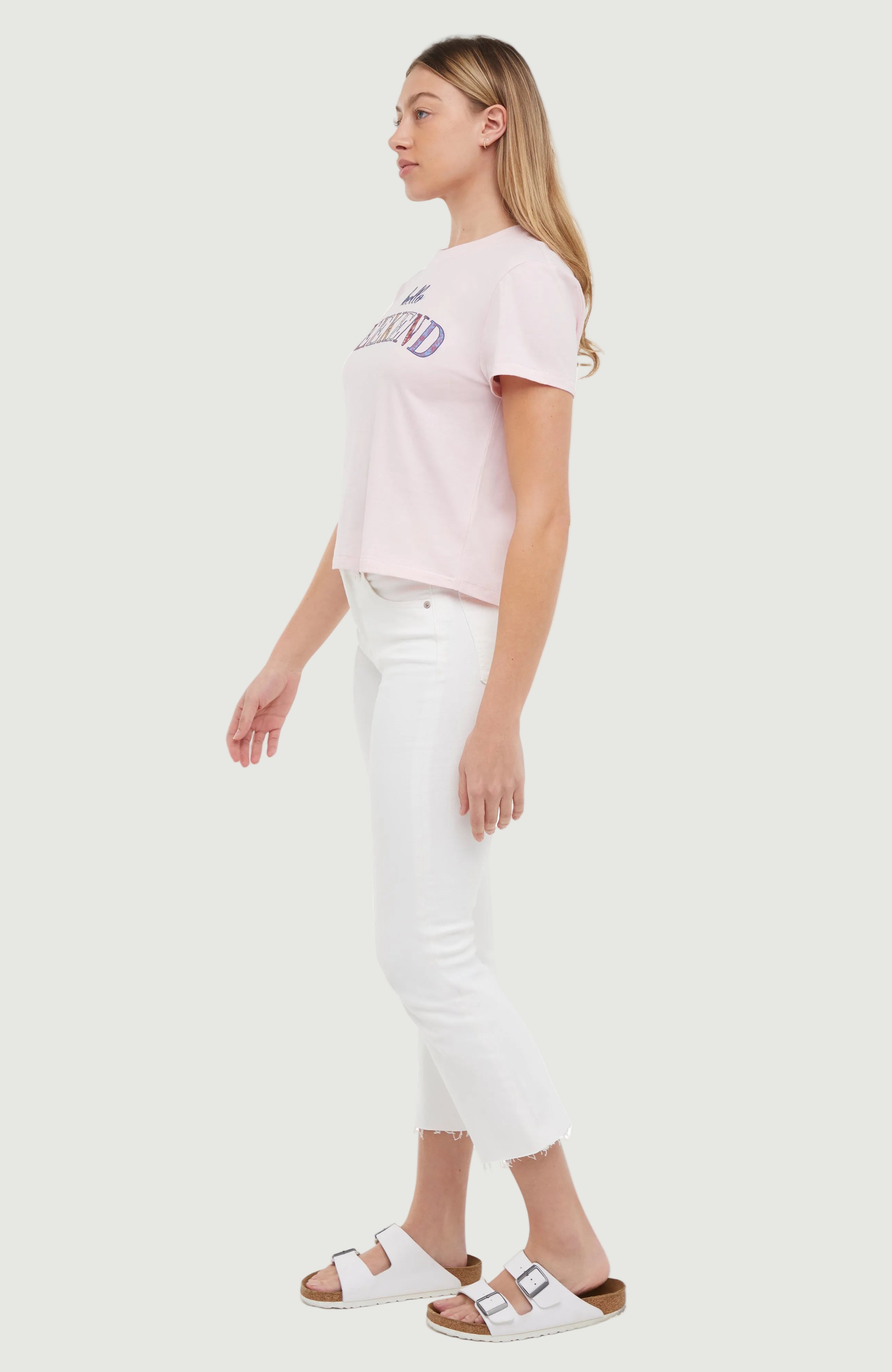 Side view of woman wearing a light pink t-shirt with colorful &