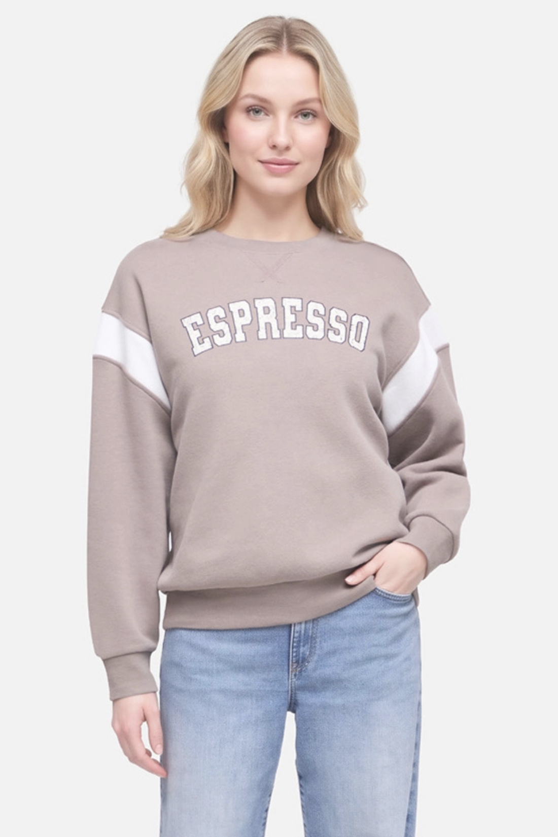 A woman wearing a taupe crewneck sweatshirt with white color-blocked sleeves and &