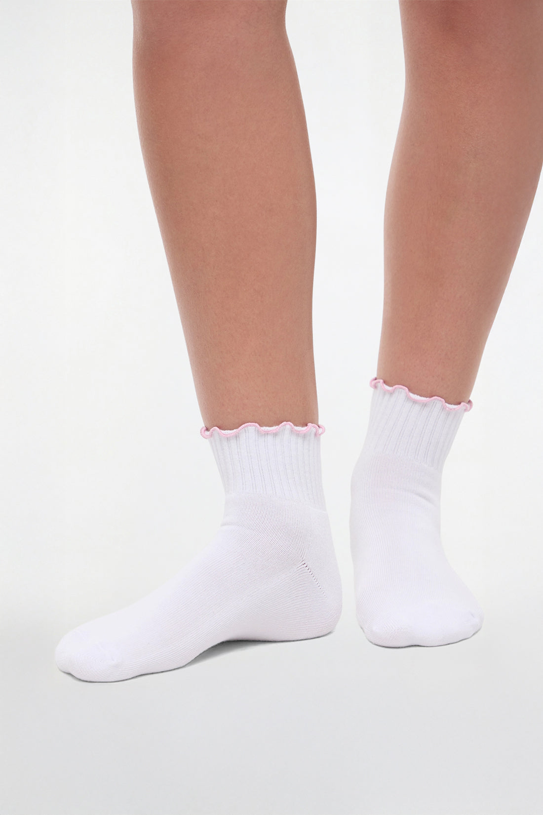 Front view of white socks with lilac ruffled trim and cheer megaphone graphic worn by a woman on a light background.