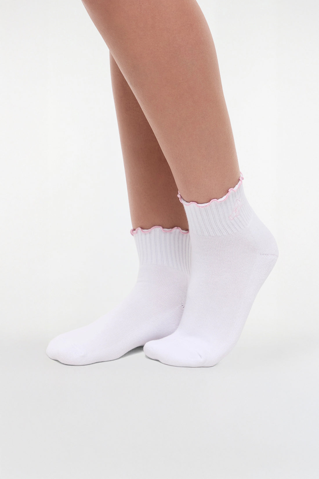 Side view of white socks with lilac ruffled trim and cheer megaphone graphic worn by a woman on a light background.
