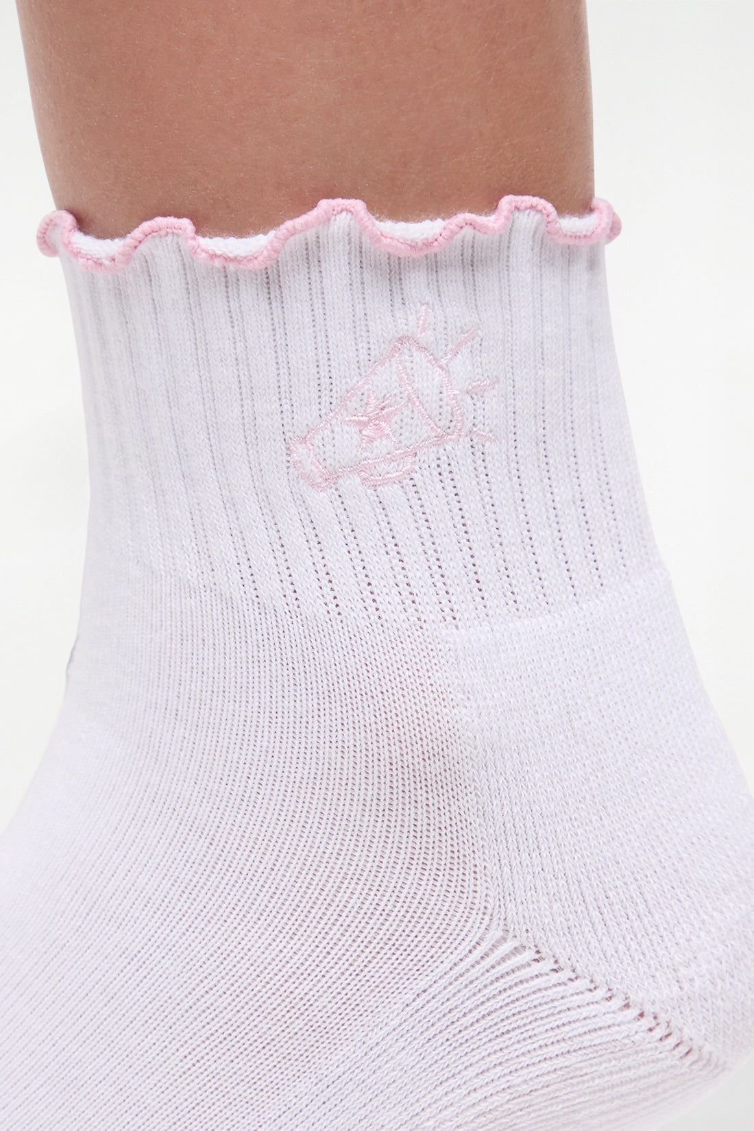 Close up view of white socks with lilac ruffled trim and cheer megaphone graphic worn by a woman on a light background.