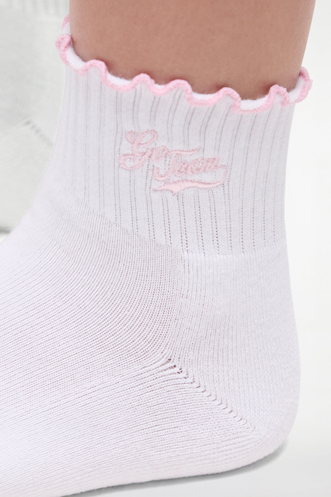 Close up view of white socks with lilac ruffled trim and &