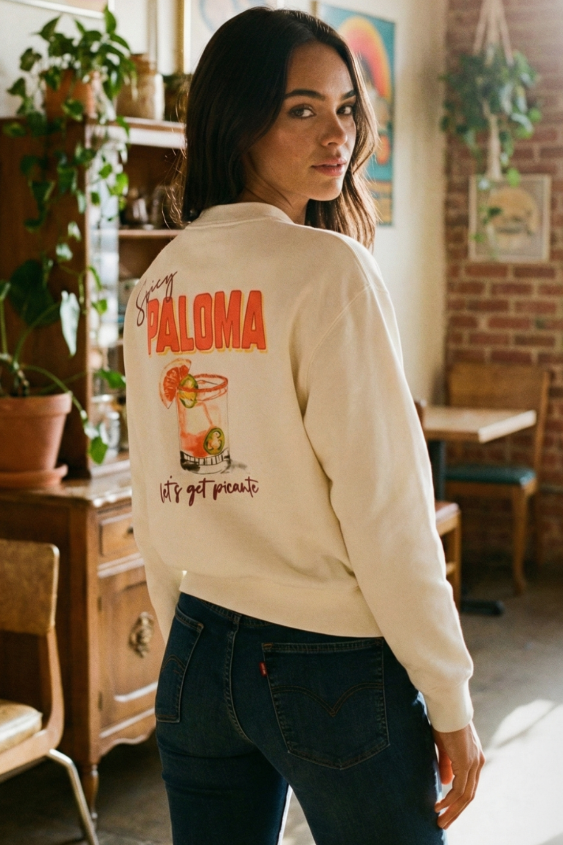 Woman wearing a white sweatshirt with a graphic design and &