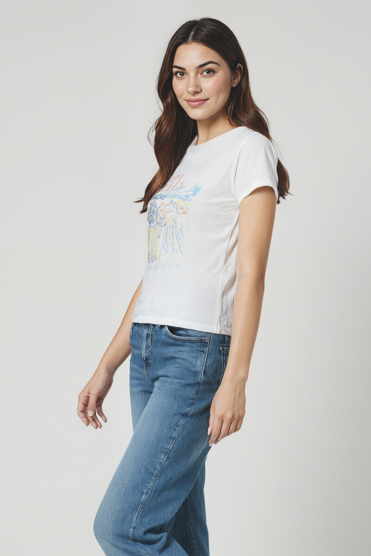 Woman wearing a white t-shirt with a graphic design that reads NAPA VALLEY CALIFORNIA on a plain background