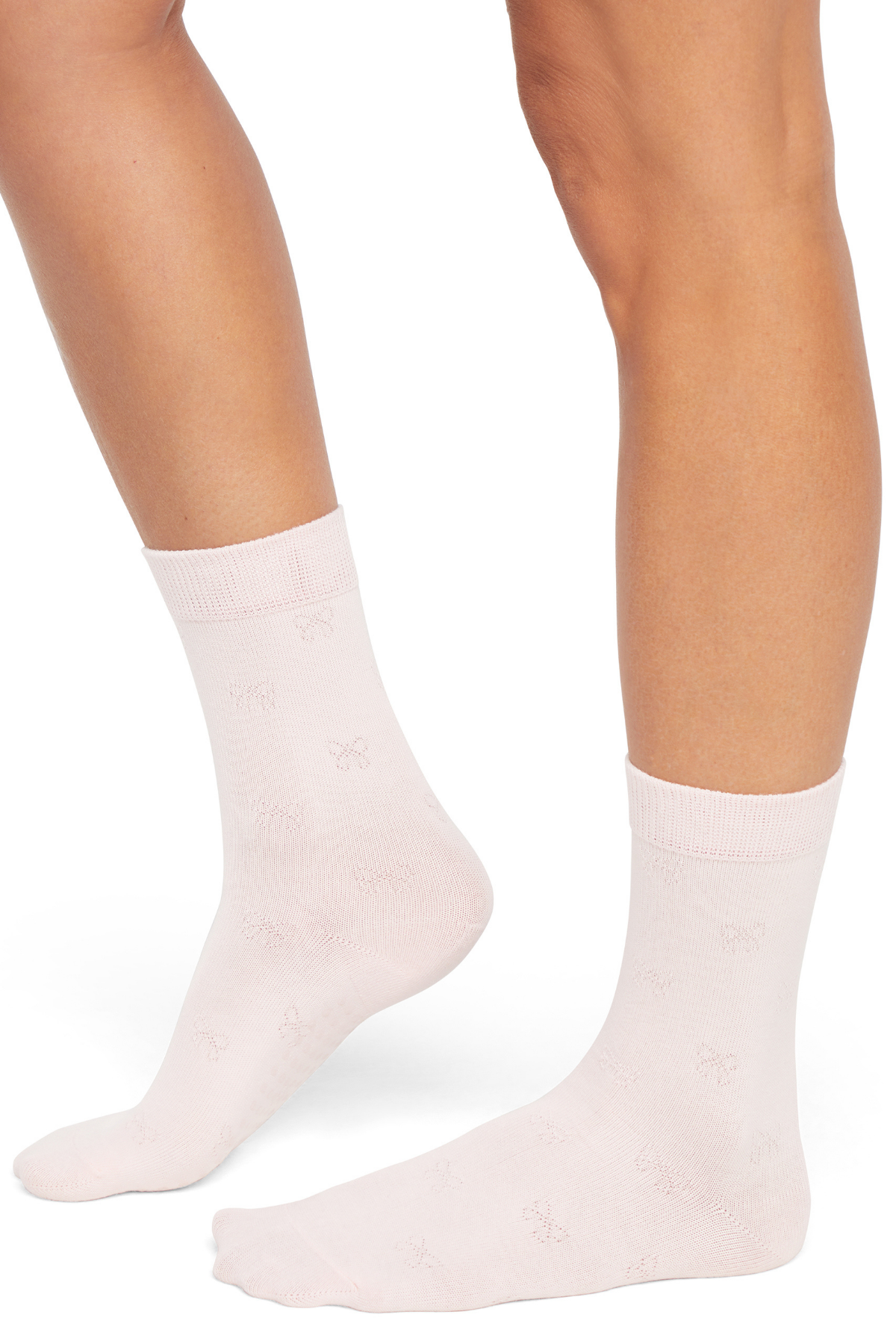 Pink socks with embossed bow print worn by a woman on a white background.